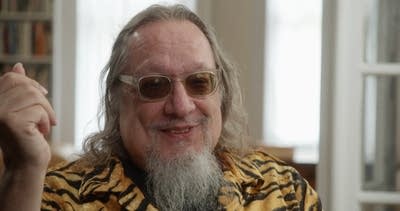 A man in sunglasses smiles during a conversation 