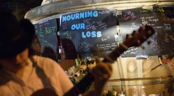 A musician sings and plays guitar during a vigil at the Legacy of Love statue in Dallas, Texas, on Sunday for victims of the attack at Orlando, Florida's Pulse Nightclub.