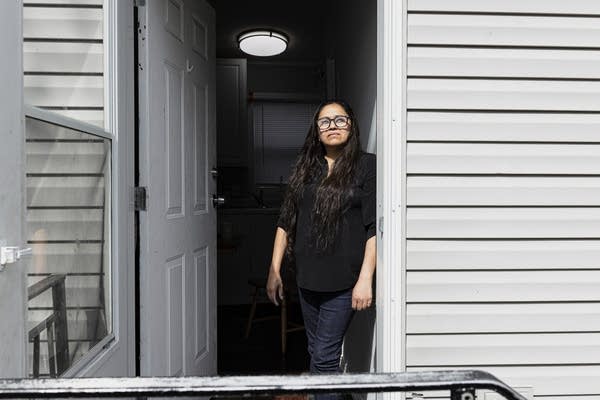 Estrella looks through the door of her home