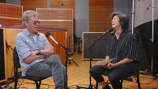 Two people have a conversation in a recording studio