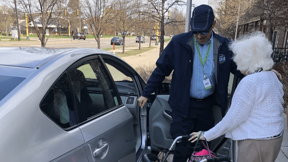 Mobility4All driver Peter Sarafolean helps rider Lois Lundemo get in the car so she can go shop for fabrics.