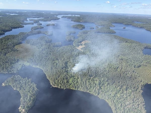 Smoke rises from a wildfire surrounded by lakes