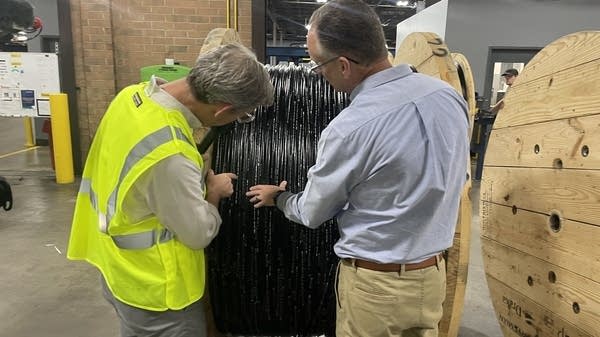 Ryssdal, left, and Prysmian cable plant director Tracy Overcash look at finished cable, imprinted with “Made in the USA,” back in 2024.