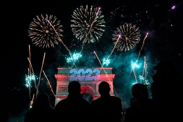 Fireworks explode next to the Arc de Triomphe with "2023" projected on the building, at the Avenue des Champs-Elysees during New Year celebrations in Paris, early on January 1, 2023. (Photo by JULIEN DE ROSA / AFP) (Photo by JULIEN DE ROSA/AFP via Getty Images)