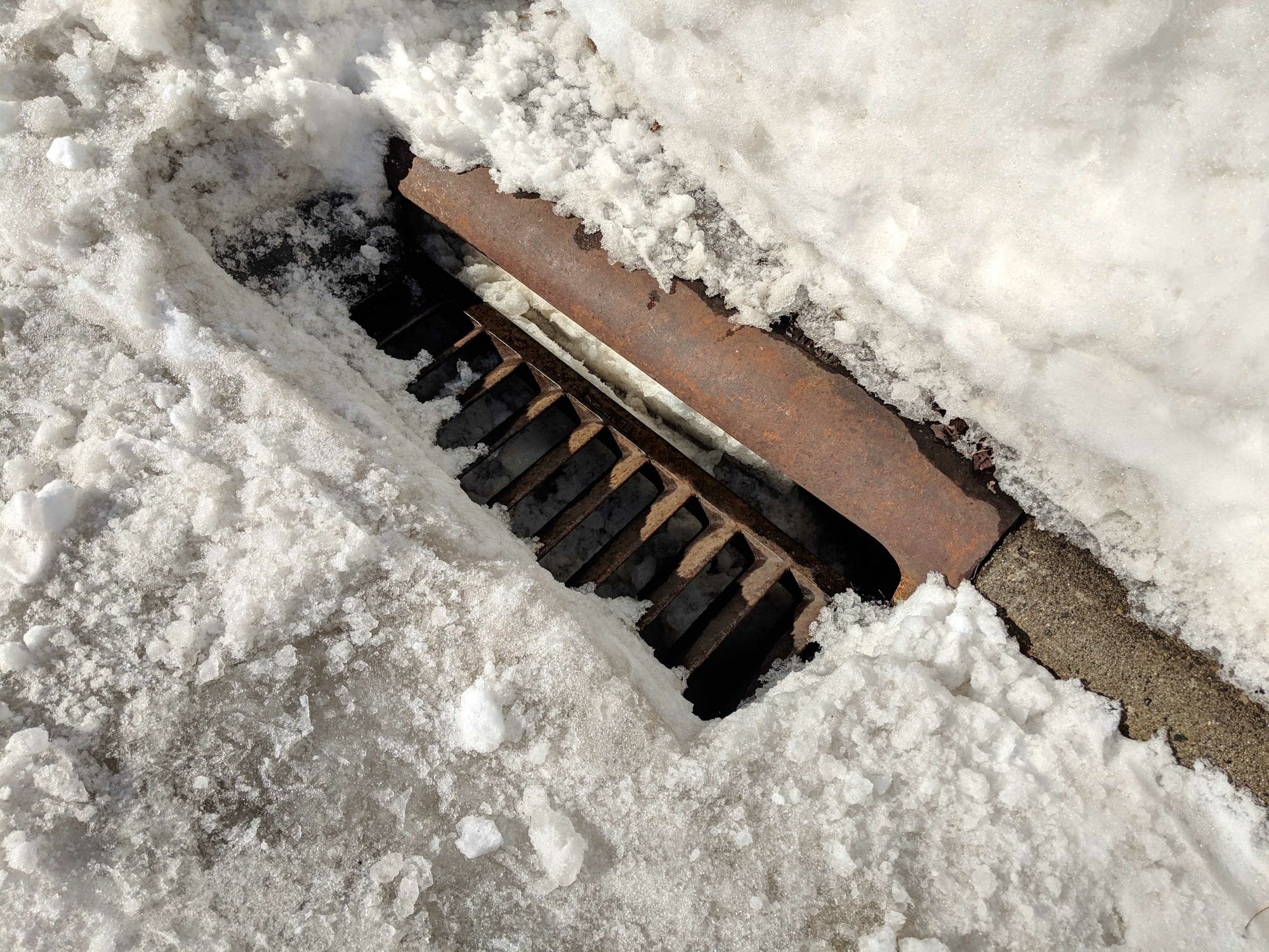 A storm drain catch basin on Fairmount Avenue in St. Paul is full of snow.