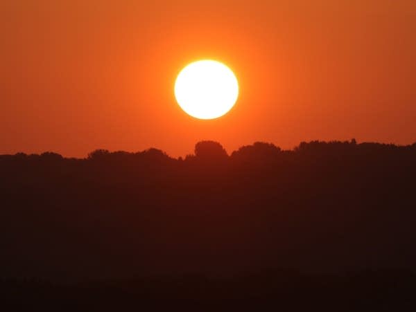 The sun rises above the Mississippi River valley at the start of another warm, hazy summer day on Saturday, July 17, 2021, as seen from South St. Paul, Minn.