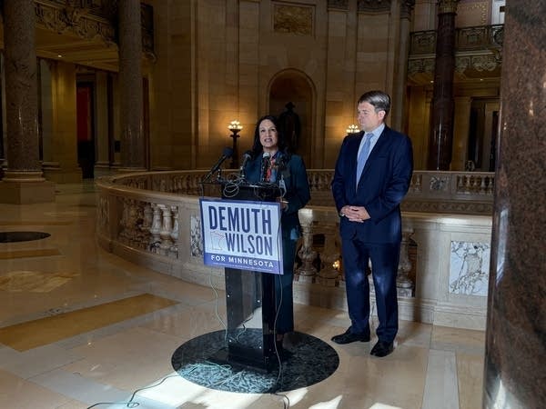Two people stand next to a podium that reads Demuth Wilson.