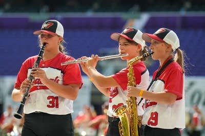 A marching band performs on the field of a football stadium.