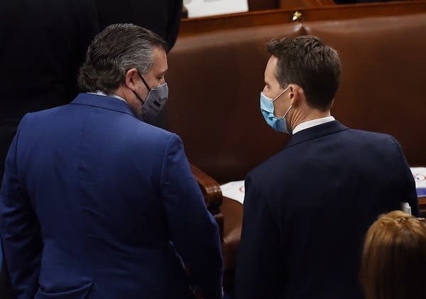 US Senator Ted Cruz, Republican of Texas, speaks with colleague Josh Hawley of Missouri during a joint session of Congress to count the electoral votes for US President at the US Capitol in Washington, DC, January 6, 2021.