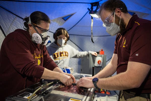 Masked researchers load fabric into a machine