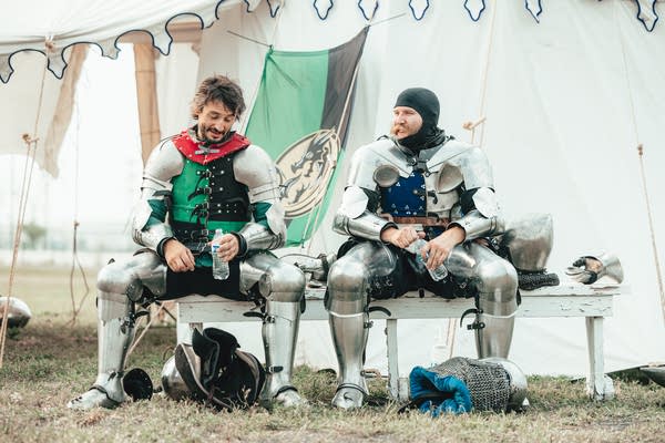 Two people sit in full suits of armor.