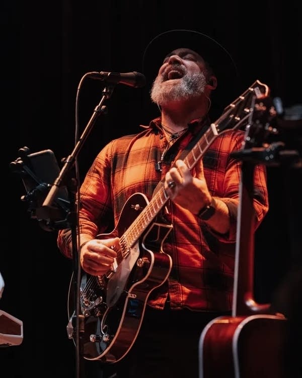 A man sings and plays guitar onstage