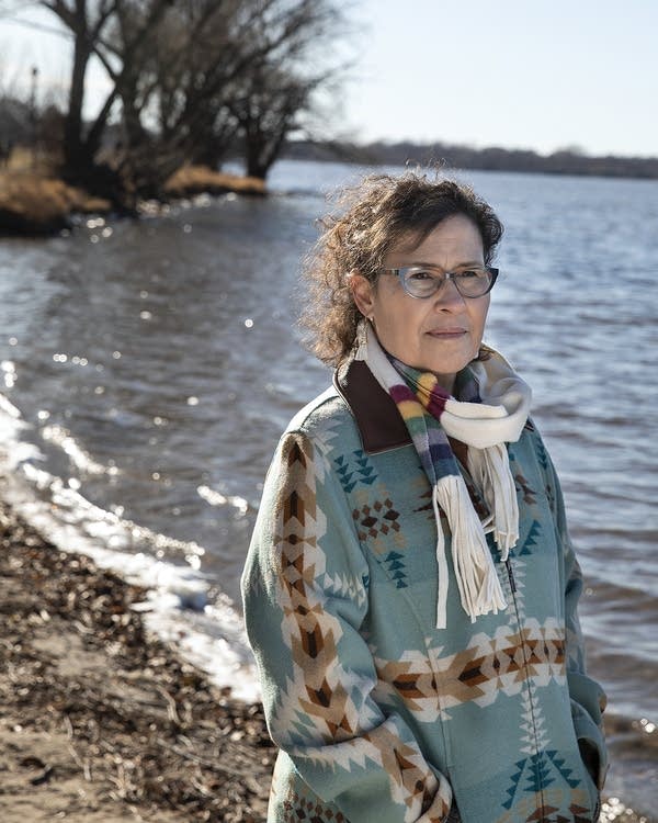 A woman stands on the lake shore. 