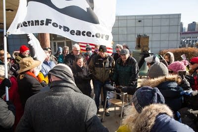 Two men stand in a group surrounded by fellow veterans.