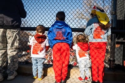 Four children stand and watch a march