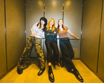 Three musicians stand together for a portrait in an elevator