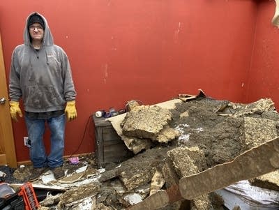 A man stands next to a pile of debris on top of a bed.