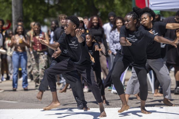 Dancers in matching black shirts perform for a crowd.