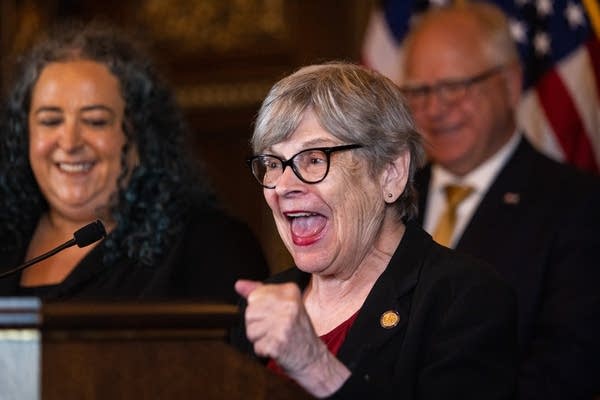 A woman speaks enthusiastically at a podium