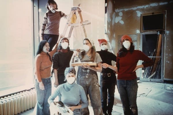 A group of people pose while working on a building renovation.