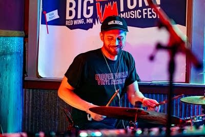A musician plays drums onstage in a music venue