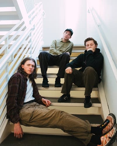 Three guys sit on a staircase together for a portrait