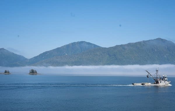 A seiner tows a small skiff along the ocean.