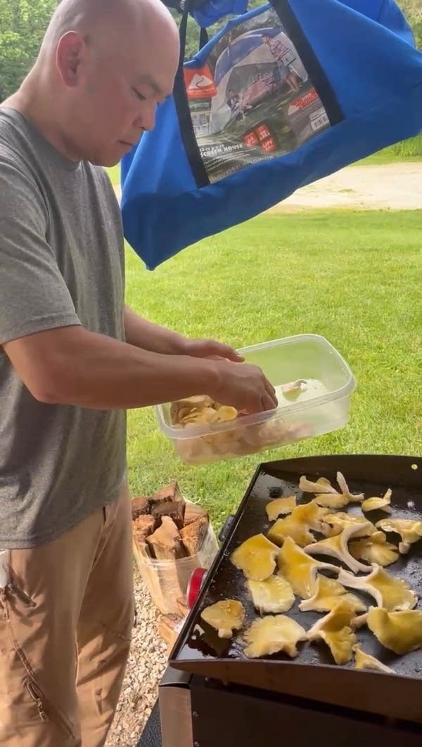 A man places wild mushrooms on a grill