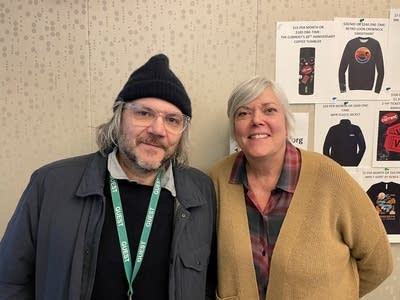Two people stand together for a portrait in a broadcast studio