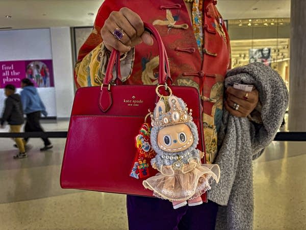 Man in red holds a red bag with a Labubu