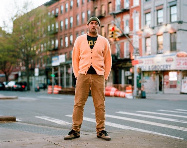 A man standing on a street corner in Harlem, New York