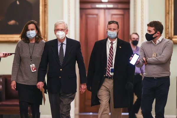 A group of people walk down a hallway.