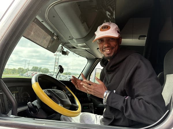 A man smiles for a photo while sitting in the cab of his truck.