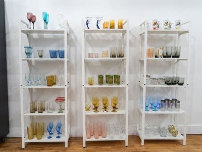 White shelves hold colorful vintage glasses.