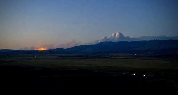 Wildfire smoke billows over some distant mountains.
