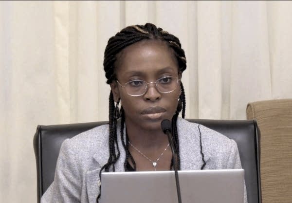 A woman sits while listening to a hearing.