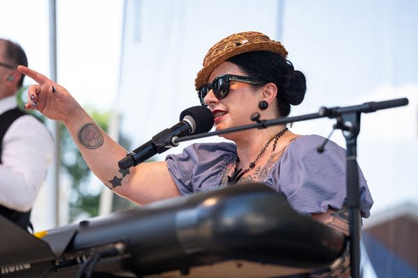 A musician sings and plays piano on an outdoor stage