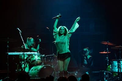 A musician sings and dances onstage in a large music venue
