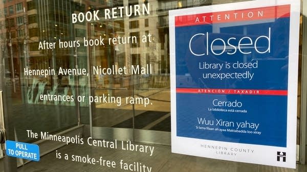 A blue closed signed taped to a glass window.