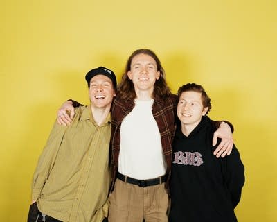 Three guys stand together and embrace for a studio portrait