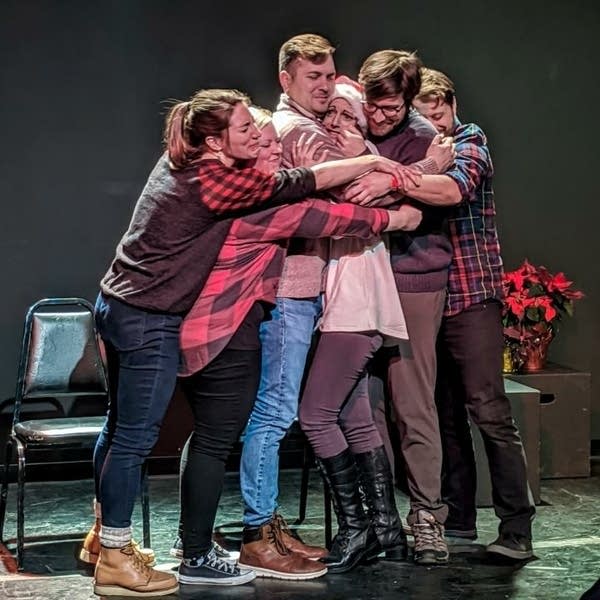 A group of people hug on a stage