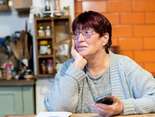 woman at table sits with phone