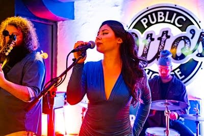 Three musicians performing onstage in a music venue