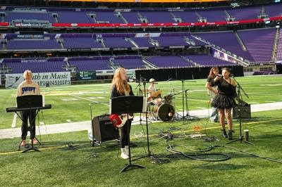 A rock band plays on the field at a football stadium.