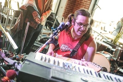 A musician plays several instruments simultaneously in a taproom