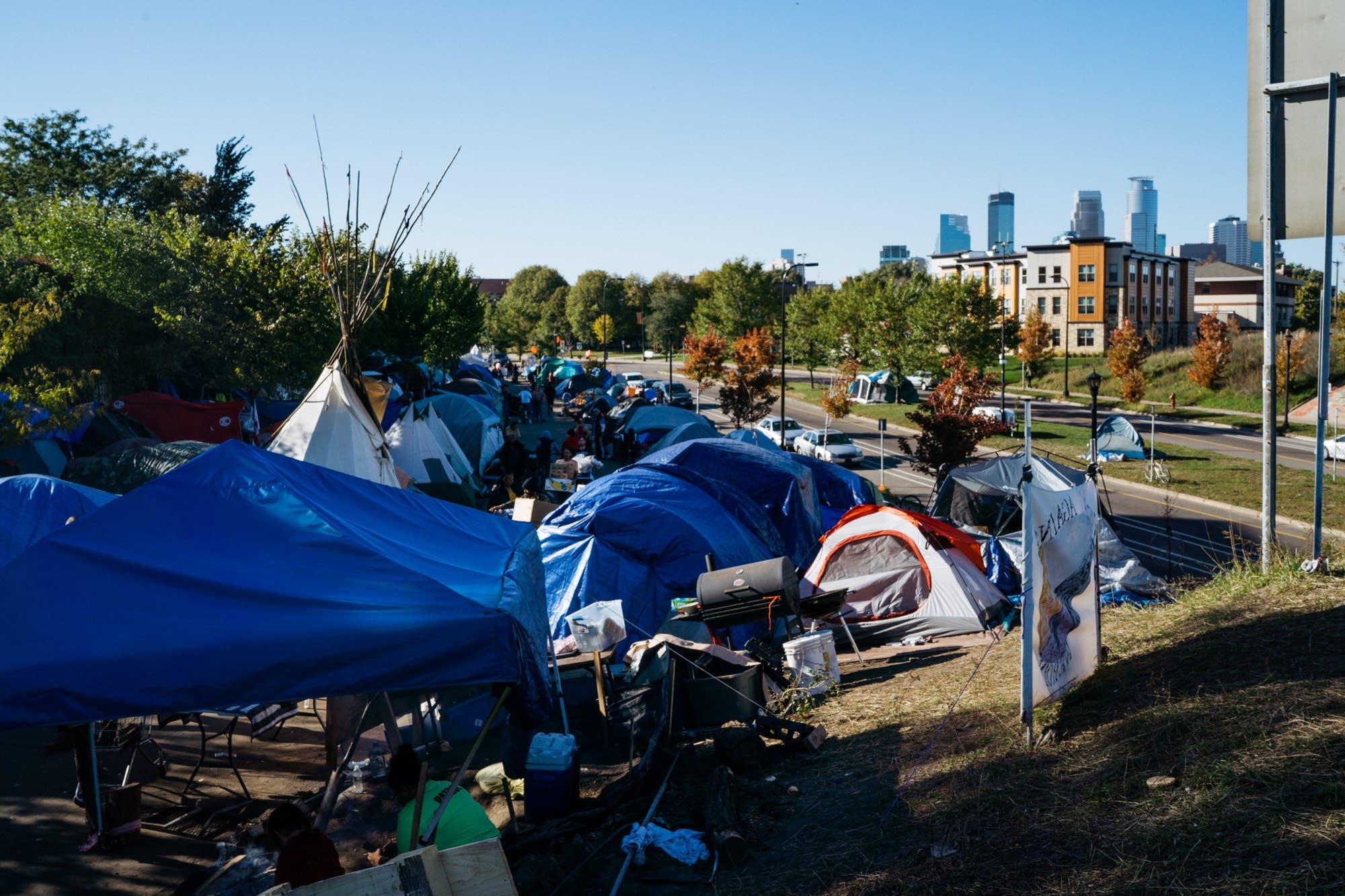 Tents fill a strip of land near Hiawatha Ave.