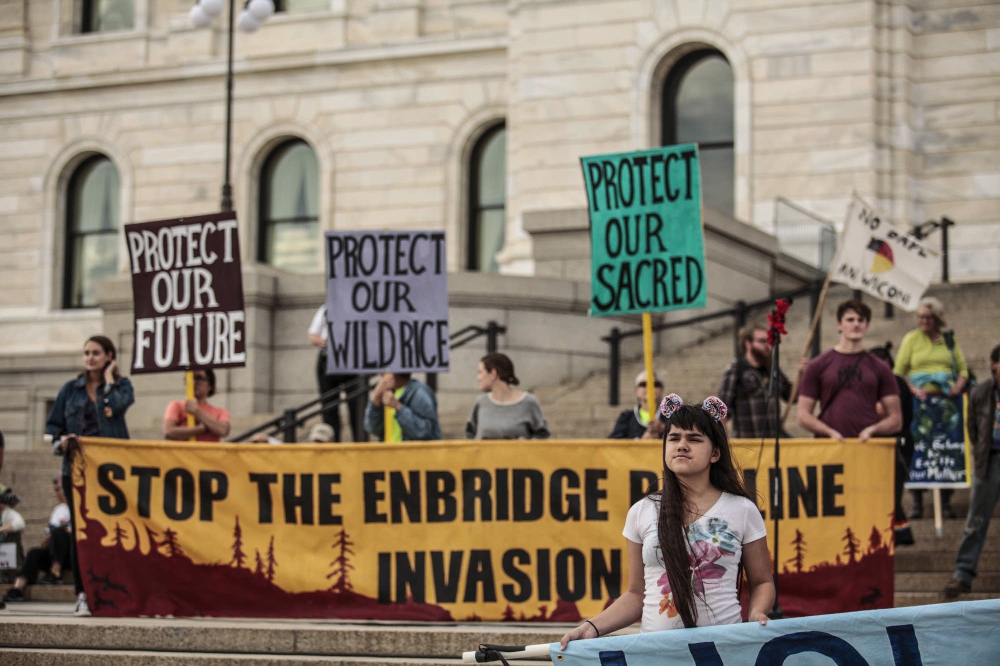 A young girl holds a sign as she stands with protesters at the Capitol.
