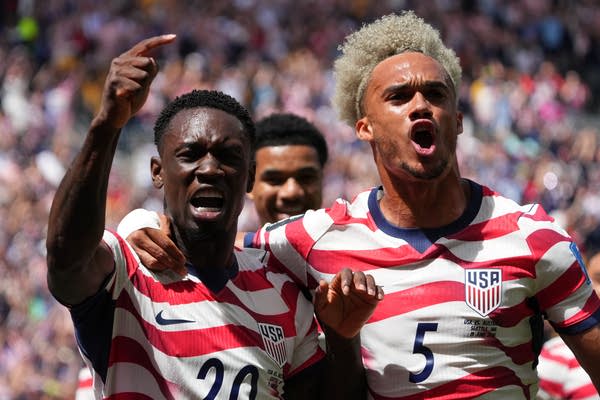 U.S. Men's Team soccer players celebrate with their arms around each other.