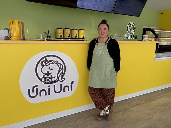 A woman stands near a counter with a sign that reads "Uni Uni."