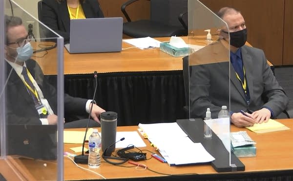 A defendant and his attorney listen as the judge speaks during a trial.